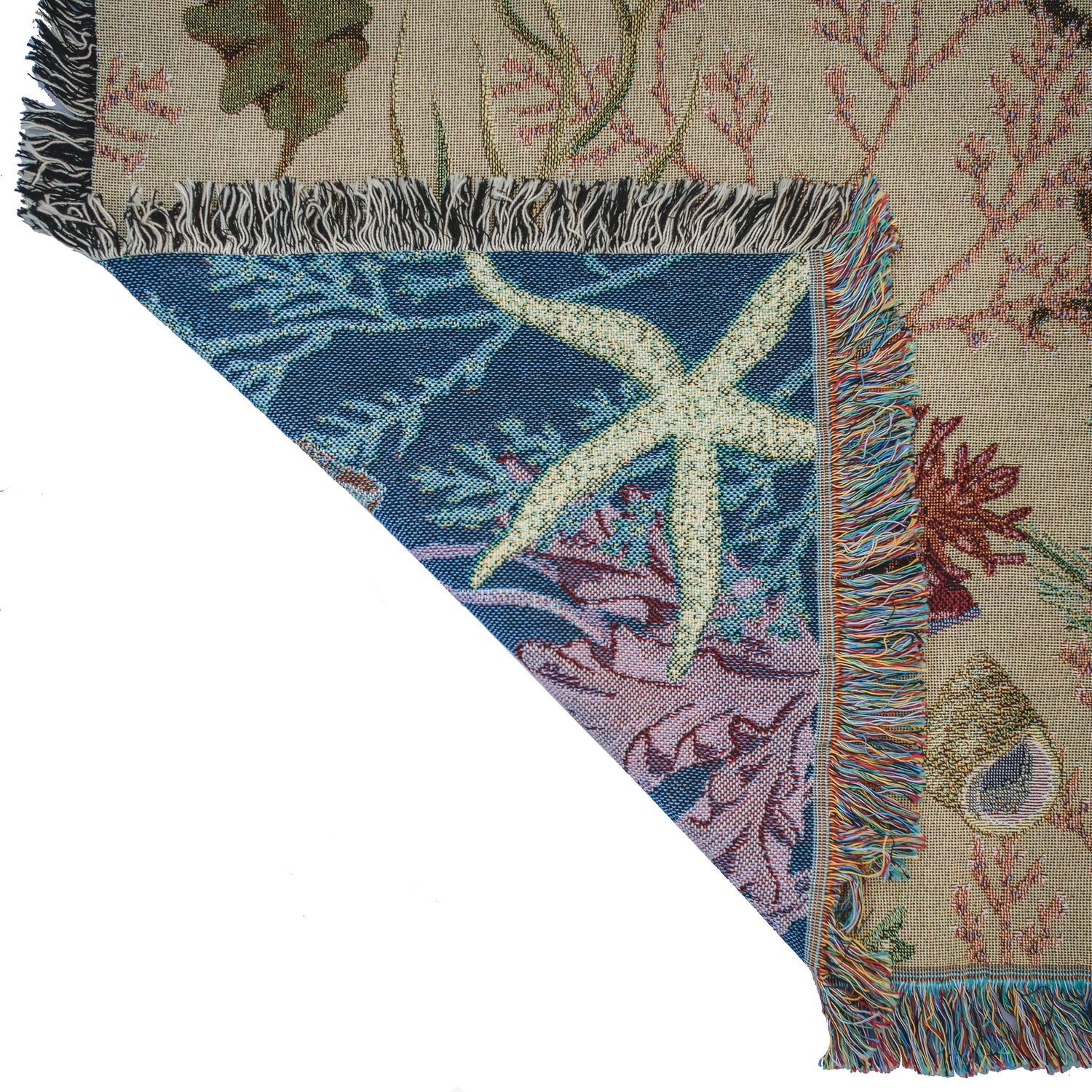 detail of woven blanket with seaweed and starfish details showing beighe front and blue reverse