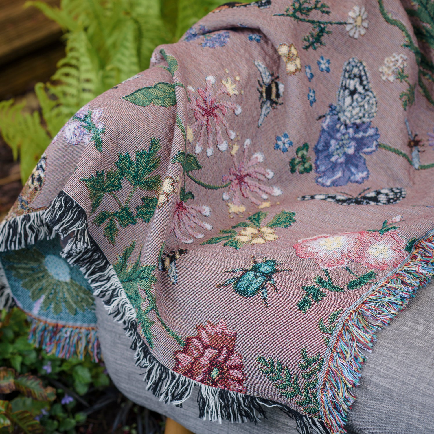 dusky pink woven wrap with bees, butterflies and flowers design draped over armchair