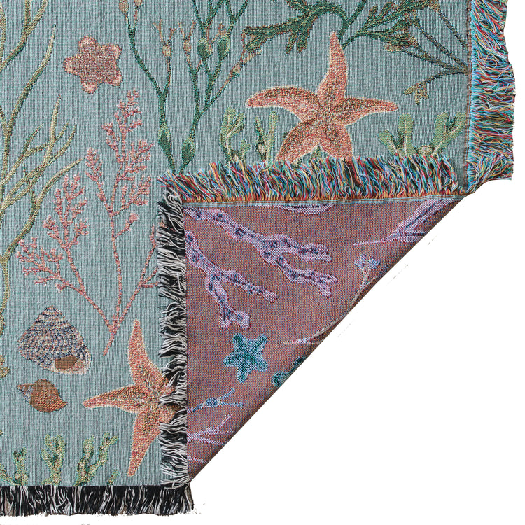 An Intertidal Star blanket with a starfish and seashells on it, by Arcana.
