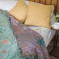 A bed with an Arcana Intertidal Star blanket and pillows on it.
