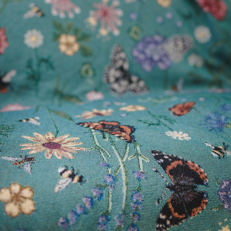 woven throw in teal with butterflies and flowers, thrown over sofa 
