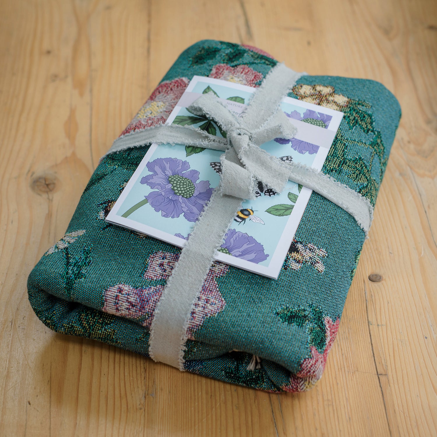 woven blanket with flowers and bees folded and wrapped with ribbon and guide