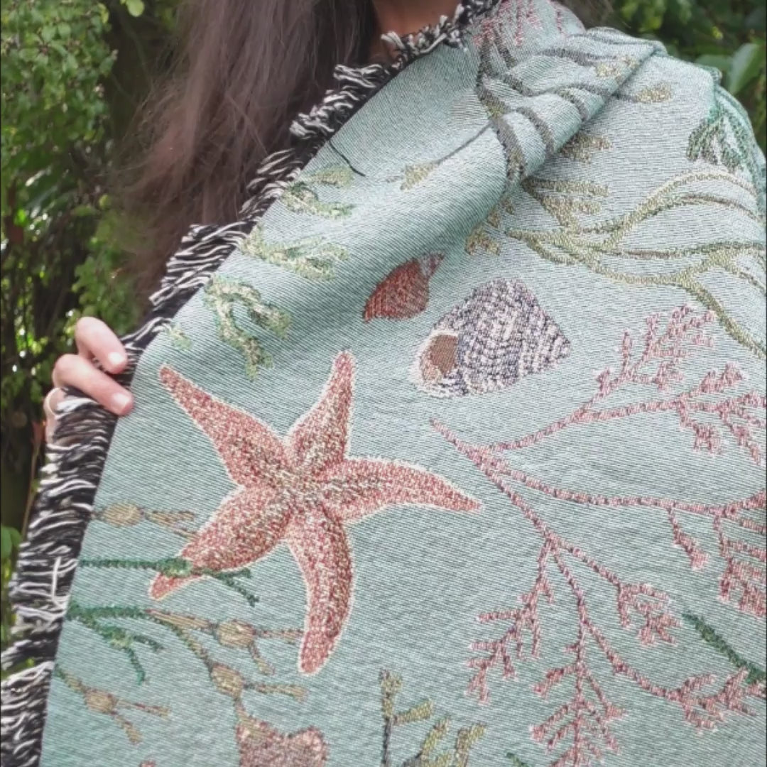 Pretty sage green blanket with sea stars and seaweed on it