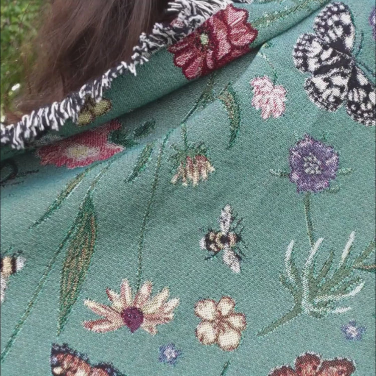 Pollination Bloom blanket from arcana held up by woman so you can see front and back