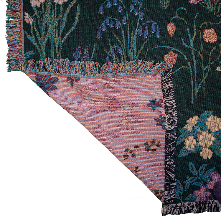 detail of Spring flowers woven blanket in dark green with light coloured fratilleries, primrose and bluebells 