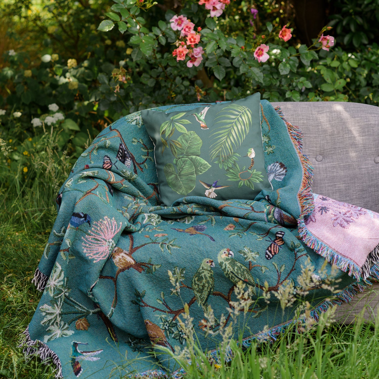 tropical bird blanket over a sofa in a summer garden with roses growing around