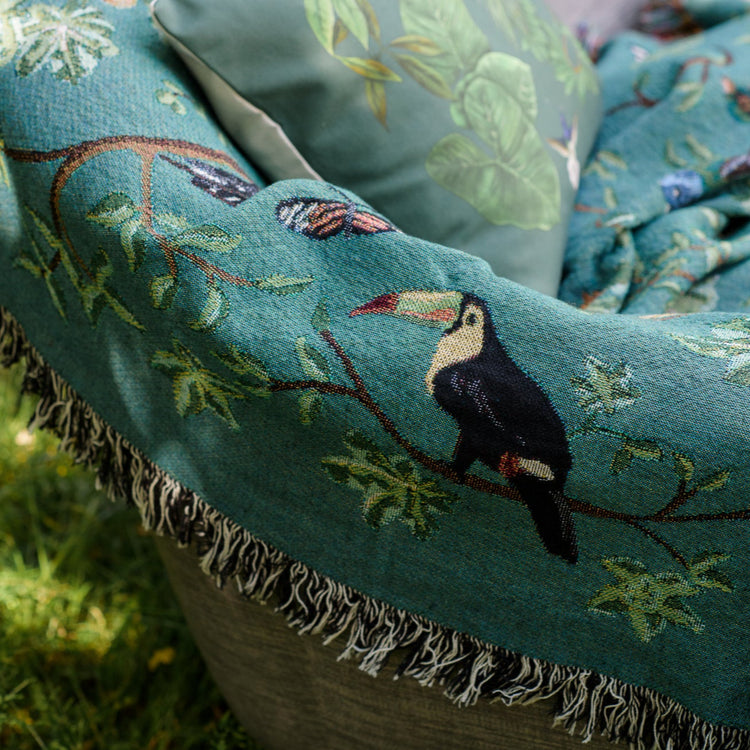 detail of woven blanket with fringe, showing tropical birds and a toucan