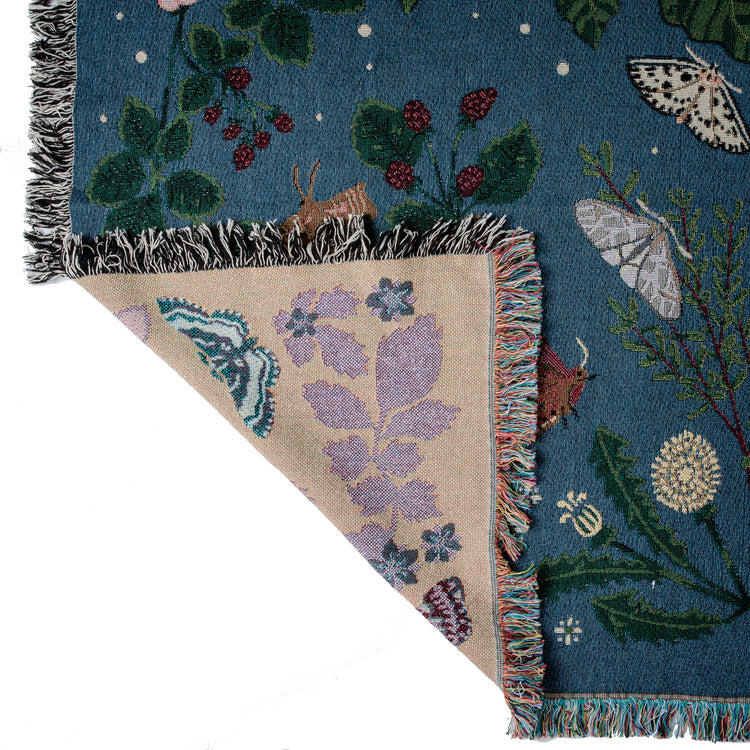detail of deep blue woven blanket with intricate moth and flower design 
