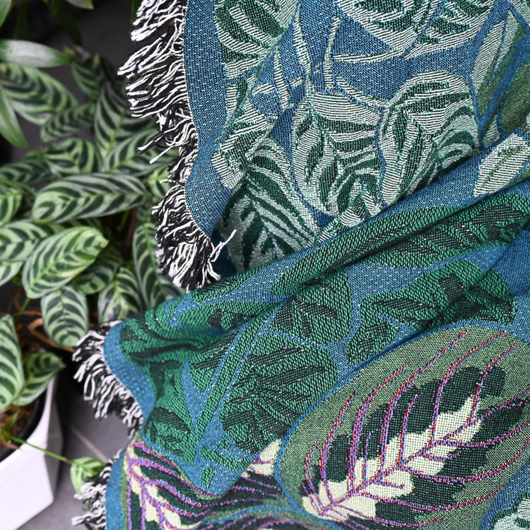 Fine details of teal and green woven blanket featuring houseplants in a airy living room with house plants all around
