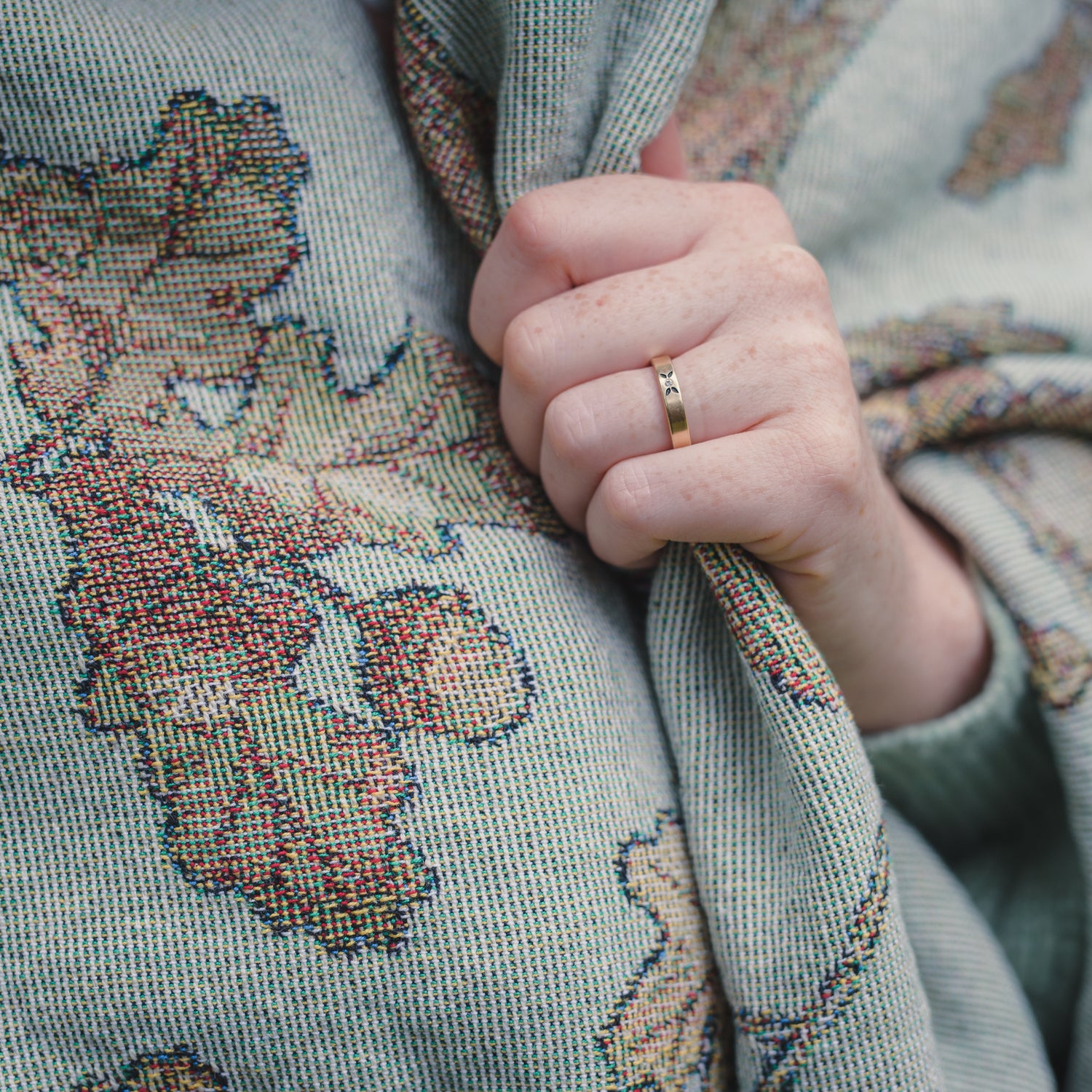 a woman wearing an Arcana Wild Oak Wrap Blanket with a ring on it.