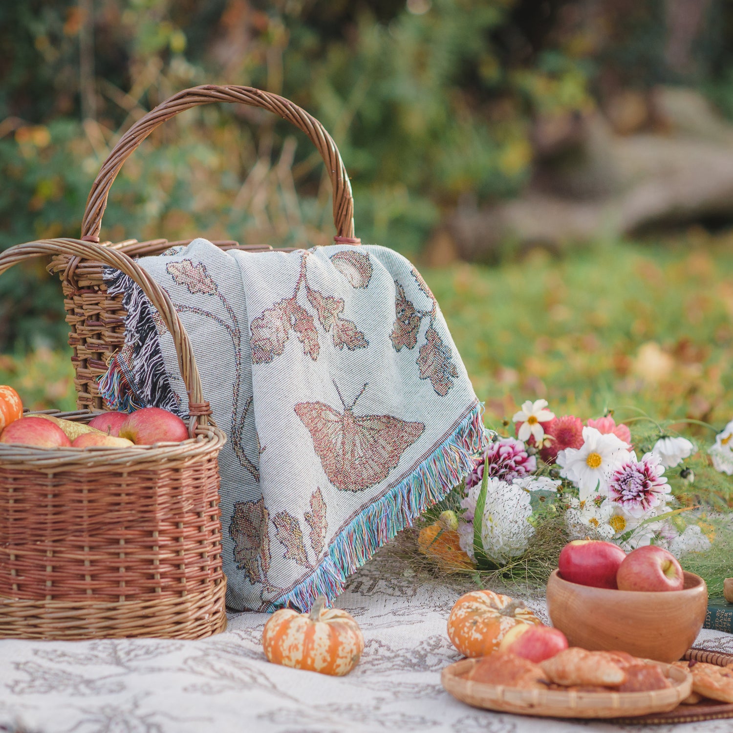 a basket of apples and a basket of bread on a Wild Oak Wrap Blanket by Arcana.