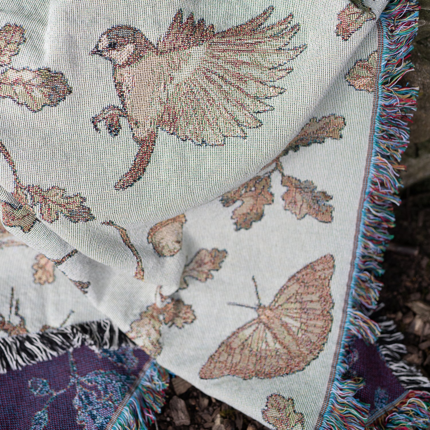 an Arcana Wild Oak Wrap Blanket with birds and butterflies on it.
